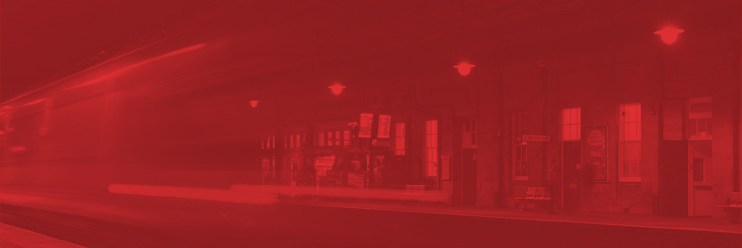 An electronic passenger information board inside a busy train station giving passengers information about destinations, departures, arrivals, delays, timings and platform numbers with a digital clock.